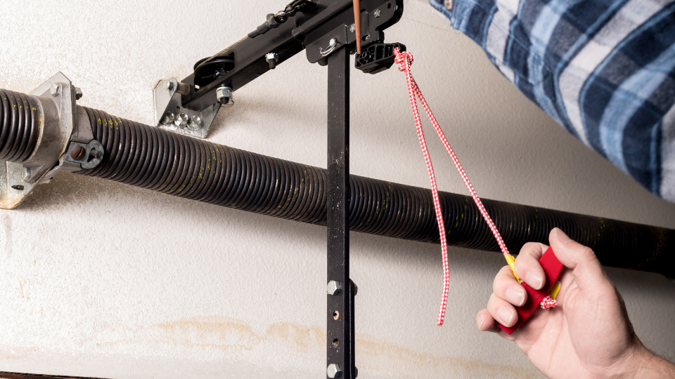 Handyman lubricates a garage door opener release leaver with a can of oil